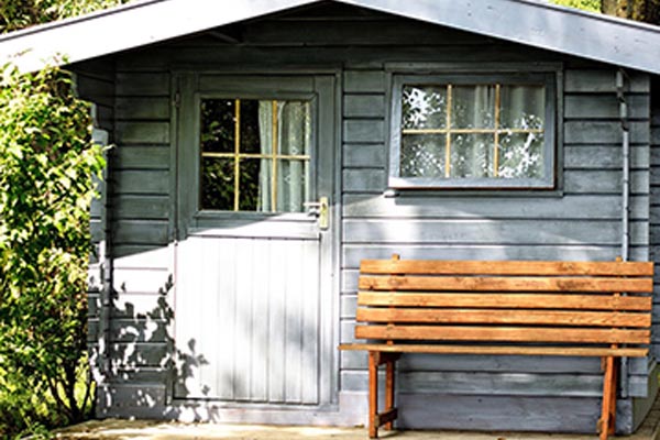 Long grey shed with plain wood bench